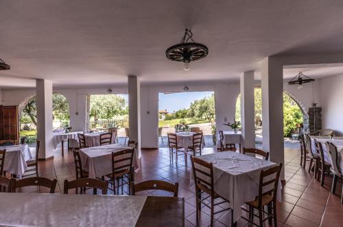 un restaurante con mesas y sillas blancas y ventanas en Affittacamere Cigui, en Muggia