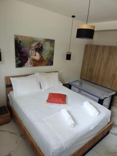 a bedroom with a white bed with a painting on the wall at Elias Studio - Near to the port of Rafina and the Airport of Athens in Áyios Spirídhon