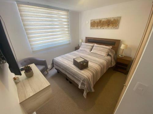 ein Schlafzimmer mit einem Bett mit einem Koffer drauf in der Unterkunft Cómodo departamento en Caldera, con piscina. in Caldera