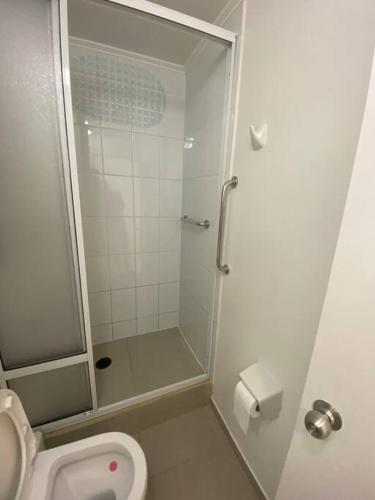 a white bathroom with a shower and a toilet at Cómodo departamento en Caldera, con piscina. in Caldera
