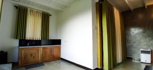um quarto com cortinas verdes e amarelas e um armário de madeira em Rain Forest Star em Deniyaya