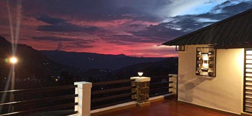 a room with a balcony with a sunset in the background at Thesula Valley in Kodaikānāl