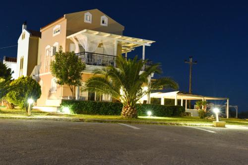 a large white building with palm trees in front of a street at Elafonisos Mare in Elafonisos