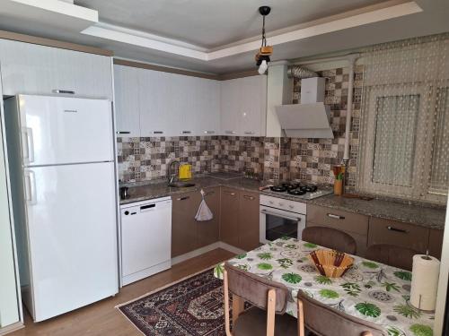 a kitchen with a table and a white refrigerator at Family Apart-Hotel 2022 - 6 in Antalya