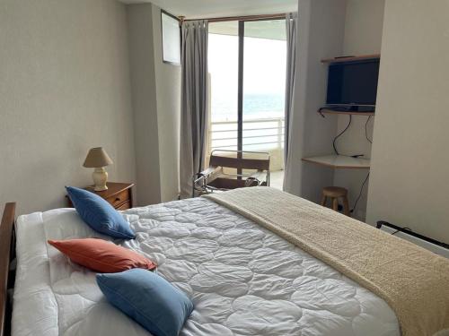 Un dormitorio con una cama grande con almohadas. en San Alfonso del Mar, Algarrobo, en Algarrobo