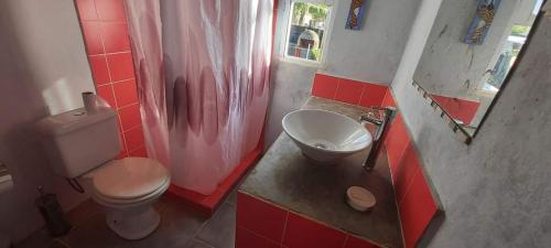 y baño con aseo, lavabo y azulejos rojos. en Lakshmi, en Neptunia