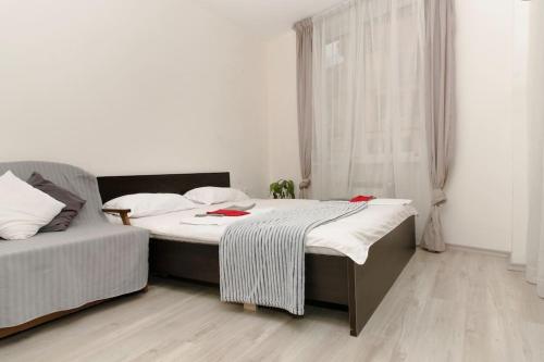 2 letti in una camera con pareti bianche e pavimenti in legno di Апартамент до парк и метро a Sofia