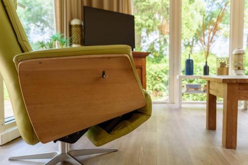 a desk with a green chair in a living room at Chalet Oakley I Ontspan in de natuur in Putten
