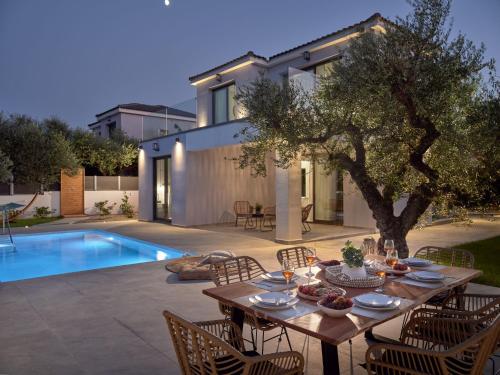 a table and chairs in front of a house at Kapodistria Luxury Villas - Serene Escape in a Scenic, Secluded Location, by ZanteWize in Plános