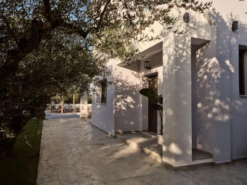 a white building with a tree in front of it at Kapodistria Luxury Villas - Serene Escape in a Scenic, Secluded Location, by ZanteWize in Plános