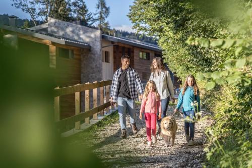 a family walking a dog down a dirt road at Camping Essenza Alpina in Folgaria