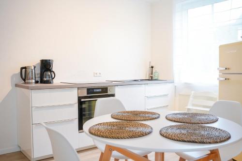 een witte keuken met een witte tafel en stoelen bij Ferienwohnung Im alten Feld in Schmallenberg