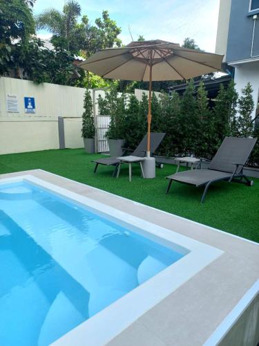 a swimming pool with an umbrella and two chairs and a table and an umbrella at Ruenthip Pattaya in Pattaya North