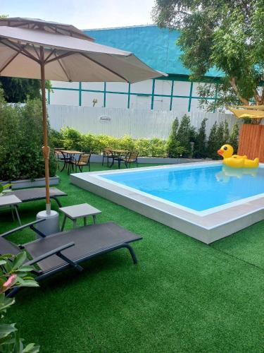 a swimming pool with green grass and an umbrella at Ruenthip Pattaya in Pattaya North