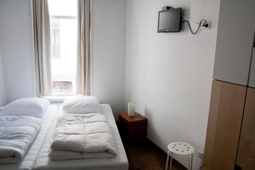 two beds in a small room with a window at City Hostel Vlissingen in Vlissingen