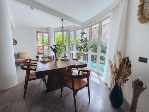 a dining room with a table and chairs and windows at Hillstone U Villa in Uluwatu