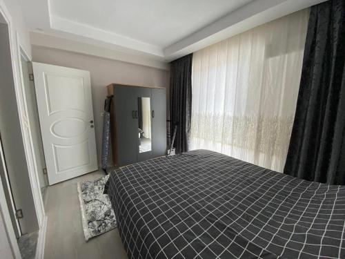 1 dormitorio con cama, ventana y espejo en DALAMAN 2+1 GENİŞ KİRALIK DAİRE, en Dalaman