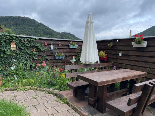 a wooden bench with an umbrella and a table at Apartment im Pfälzerwald in Lambrecht
