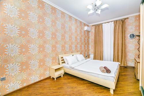 a bedroom with a bed and a wall covered in wallpaper at Apartment Lux in Baku