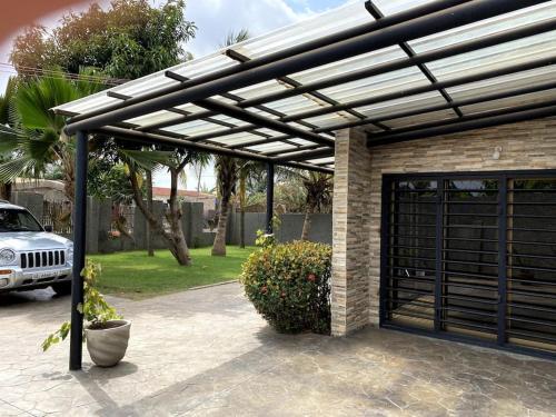 a pergola over a garage with a car at Relaxinhaatso - 4 Bedroom luxury house with pool in Haatso