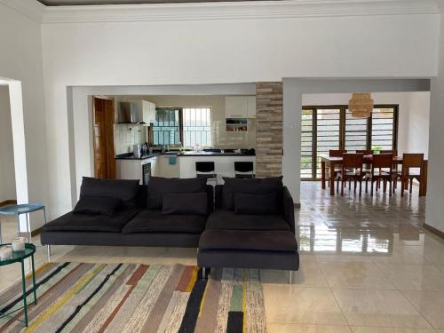 a living room with a couch and a kitchen at Relaxinhaatso - 4 Bedroom luxury house with pool in Haatso