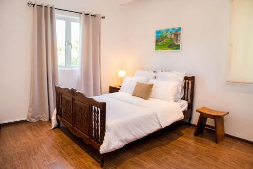Schlafzimmer mit einem Bett mit weißer Bettwäsche und einem Fenster in der Unterkunft Island Villa in Grand-Gaube