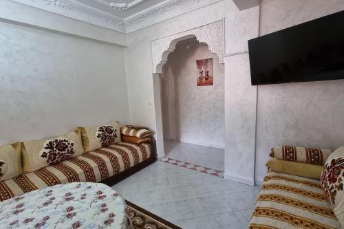 Airport apartment في مراكش: غرفة معيشة مع كنبتين وتلفزيون بشاشة مسطحة