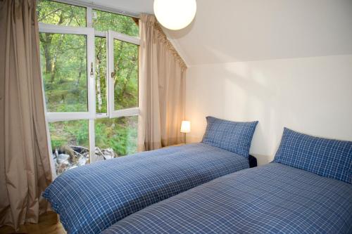 2 camas num quarto com uma janela em Lochleven Seafood Cottage em Onich