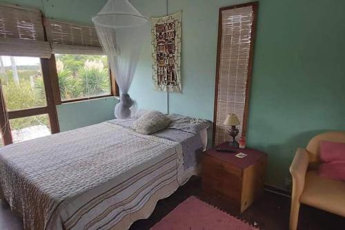 een slaapkamer met een bed, een stoel en ramen bij Maitri in Neptunia