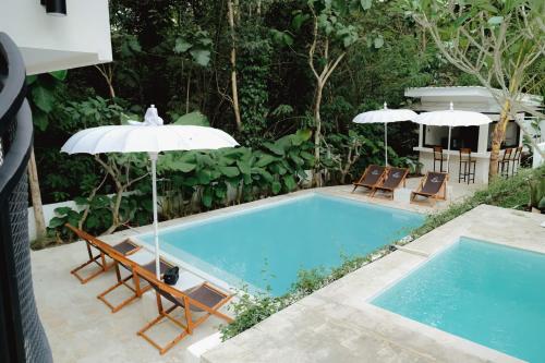 a swimming pool with chairs and umbrellas next to it at The Volter Yogyakarta in Ngingas