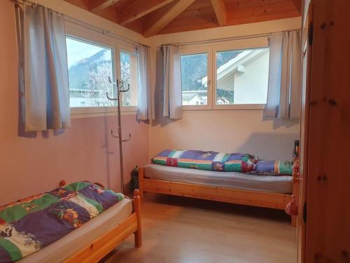 two beds in a room with two windows at Casa Nadja, nähe Skigebiet Flims-Lax in Ems