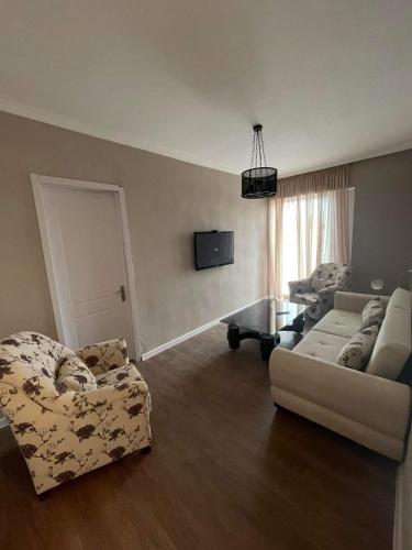 a living room with two chairs and a couch and a tv at Tsius apartment in Kutaisi