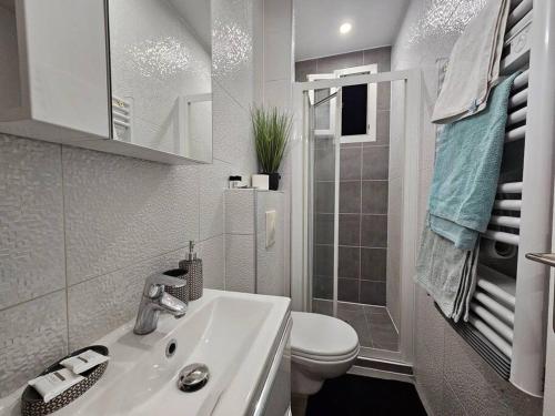 a white bathroom with a toilet and a sink at Appartement Proche Metro Paris in Pantin