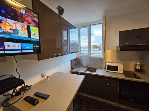 a kitchen with a tv and a table with a microwave at Appartement Proche Metro Paris in Pantin