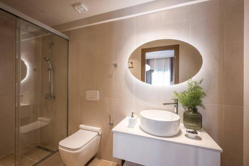 a bathroom with a sink and a toilet and a mirror at Amalia's Luxury Apartment 1 in Heraklio