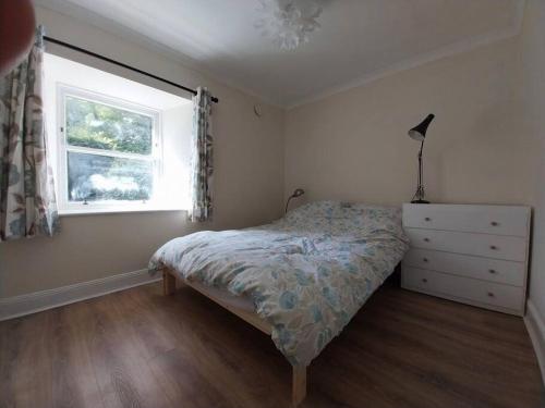 a bedroom with a bed and a window and a dresser at Idyllic cottage in peaceful rural location in Helensburgh