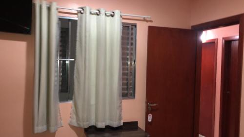 a bathroom with a white shower curtain and a window at Trilhos Hotel in Sao Paulo