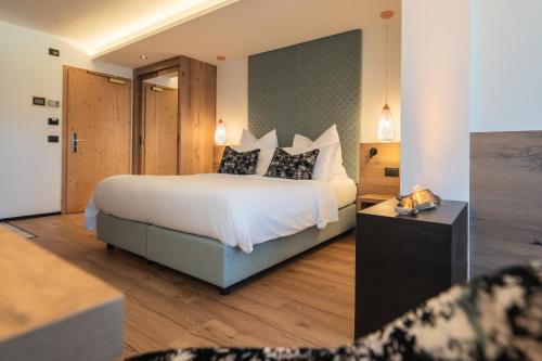 a hotel room with a bed with white sheets and pillows at Hotel Garden in Moena