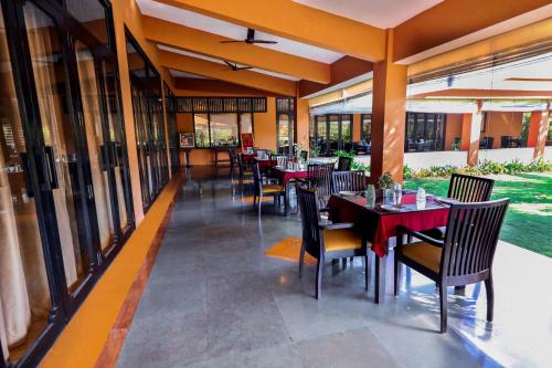 a restaurant with tables and chairs and windows at Blue Ocean The Fern Resort & Spa Ganpatipule in Ganpatipule