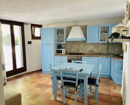 cocina con armarios azules, mesa y sillas en Villa Malva Apartment, en Torre delle Stelle