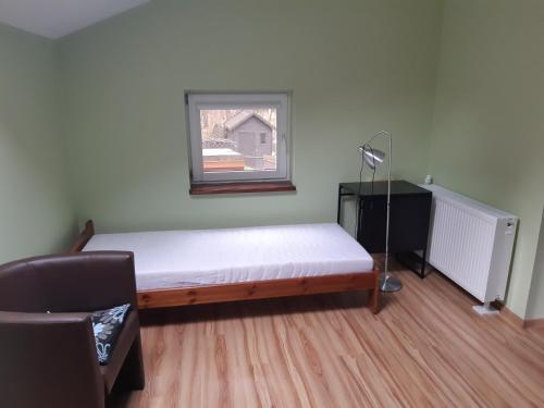 a bedroom with a bed and a window and a chair at UROCZYSKO POD LASEM in Mikoszewo
