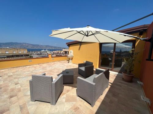 un patio con 2 sillas y una sombrilla en B&B Around the World, en Villa San Giovanni