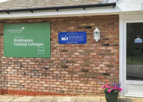 a brick building with a sign on it at Bridlington Holiday Cottages in Fraisthorpe