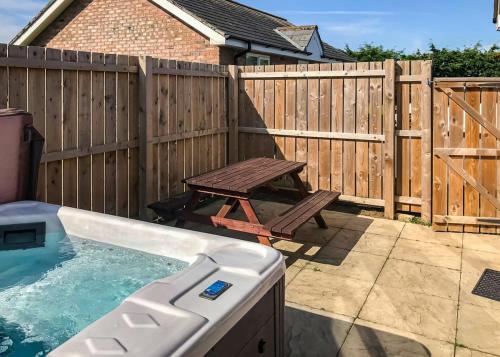 a backyard with a wooden fence and a wooden picnic table at Bridlington Holiday Cottages in Fraisthorpe