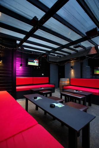 a room with red couches and tables and a tv at The Saddle Inn in Chester