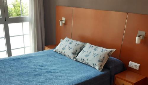 a bedroom with a bed with a headboard and a pillow at Pensión Aneira in Puebla de Trives