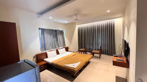 a bedroom with a bed and a desk and a television at Hotel Sumanchandra Suites in Nashik