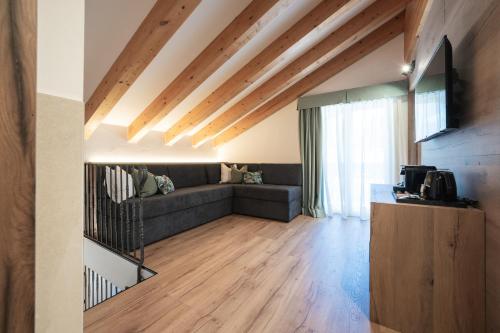 a living room with a couch and wooden floors at Hotel Garden in Moena