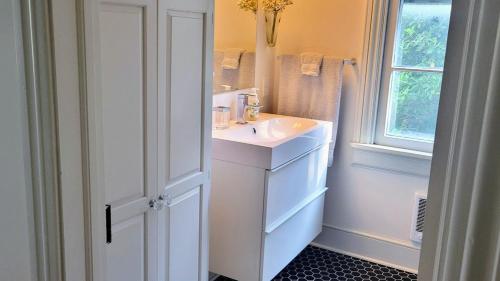 baño blanco con lavabo y ventana en Pinetown Bridge Bnb LLC, 