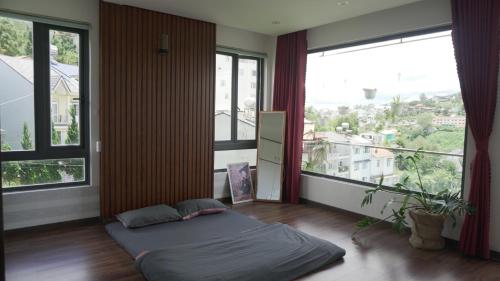 a bedroom with a bed in front of large windows at Hoshi DaLat House in Da Lat